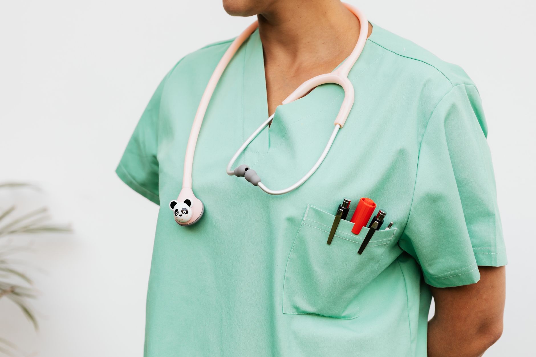 Close-up of a doctor in scrubs with a panda themed stethoscope and pocket pens.