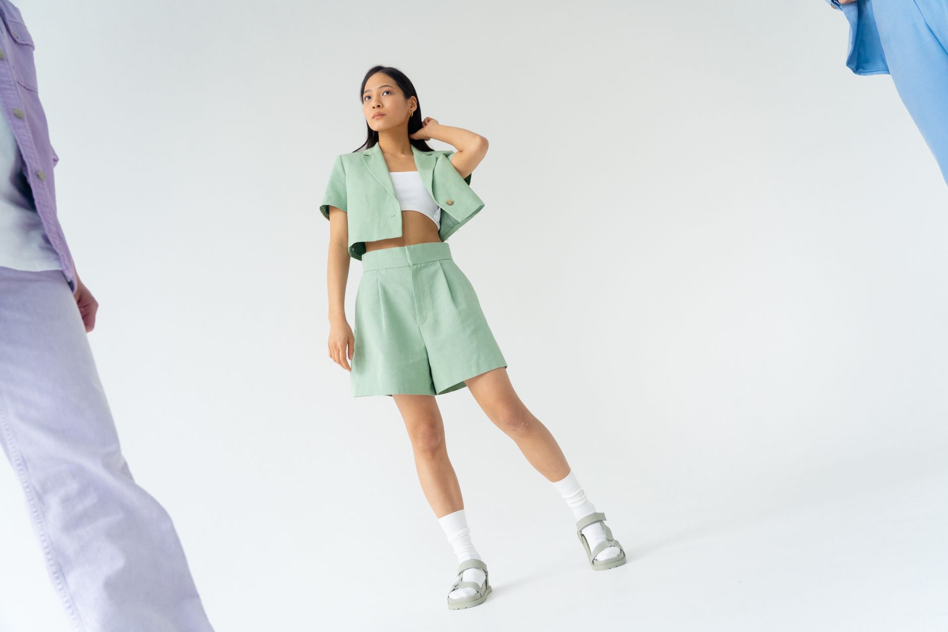 Fashionable Asian woman in a mint green outfit posing against a white studio background.