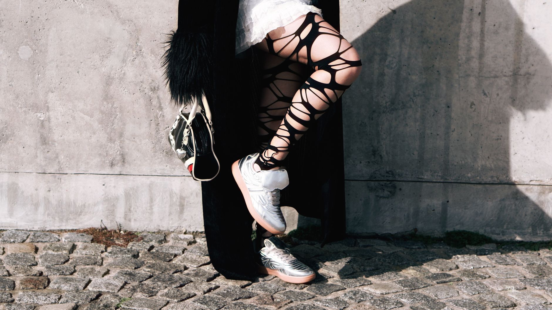 Stylish urban fashion featuring edgy tights and sneakers in an outdoor setting.