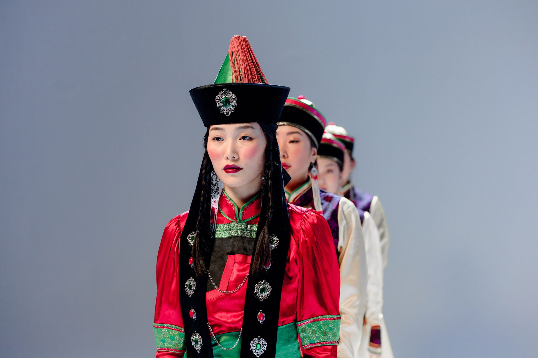 A group of East Asian women wearing colorful traditional dresses, posing in a studio setting.