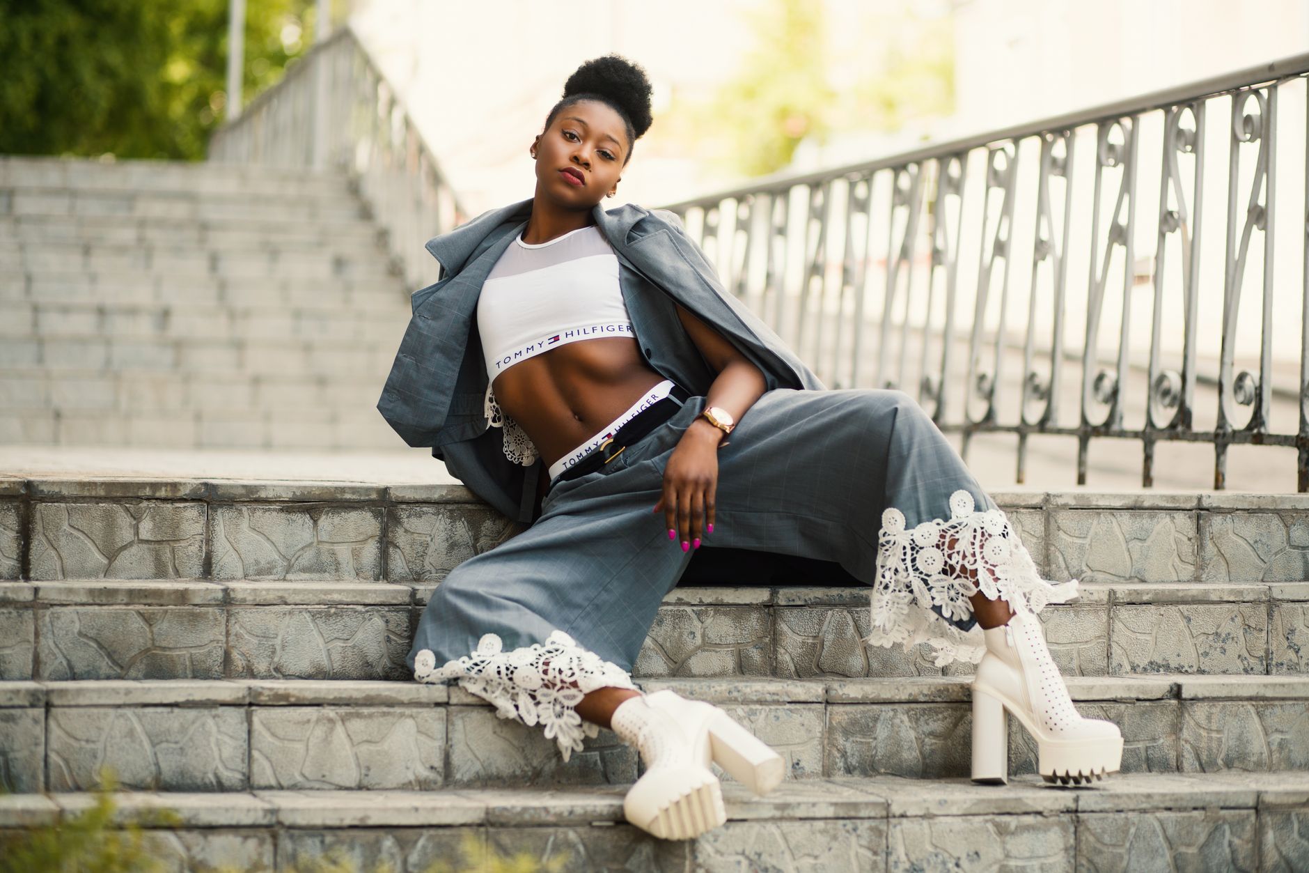 Fashionable woman posing stylishly on city steps in chic outfit.