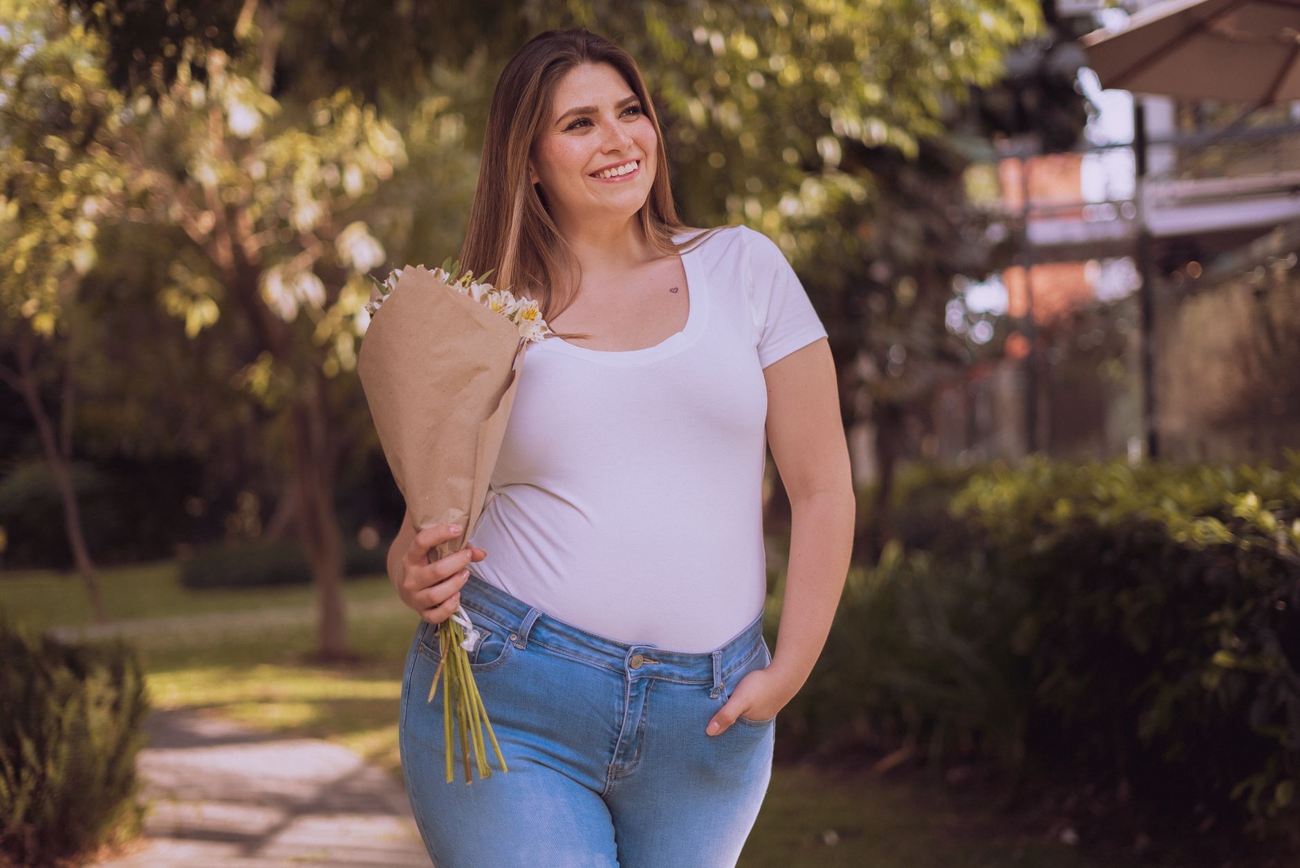 Happy woman holding a bouquet of flowers in a sunny park setting, radiating positivity.