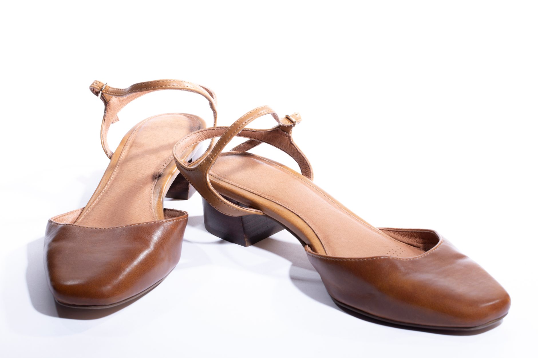 Pair of stylish brown leather strap heeled sandals on a white background.