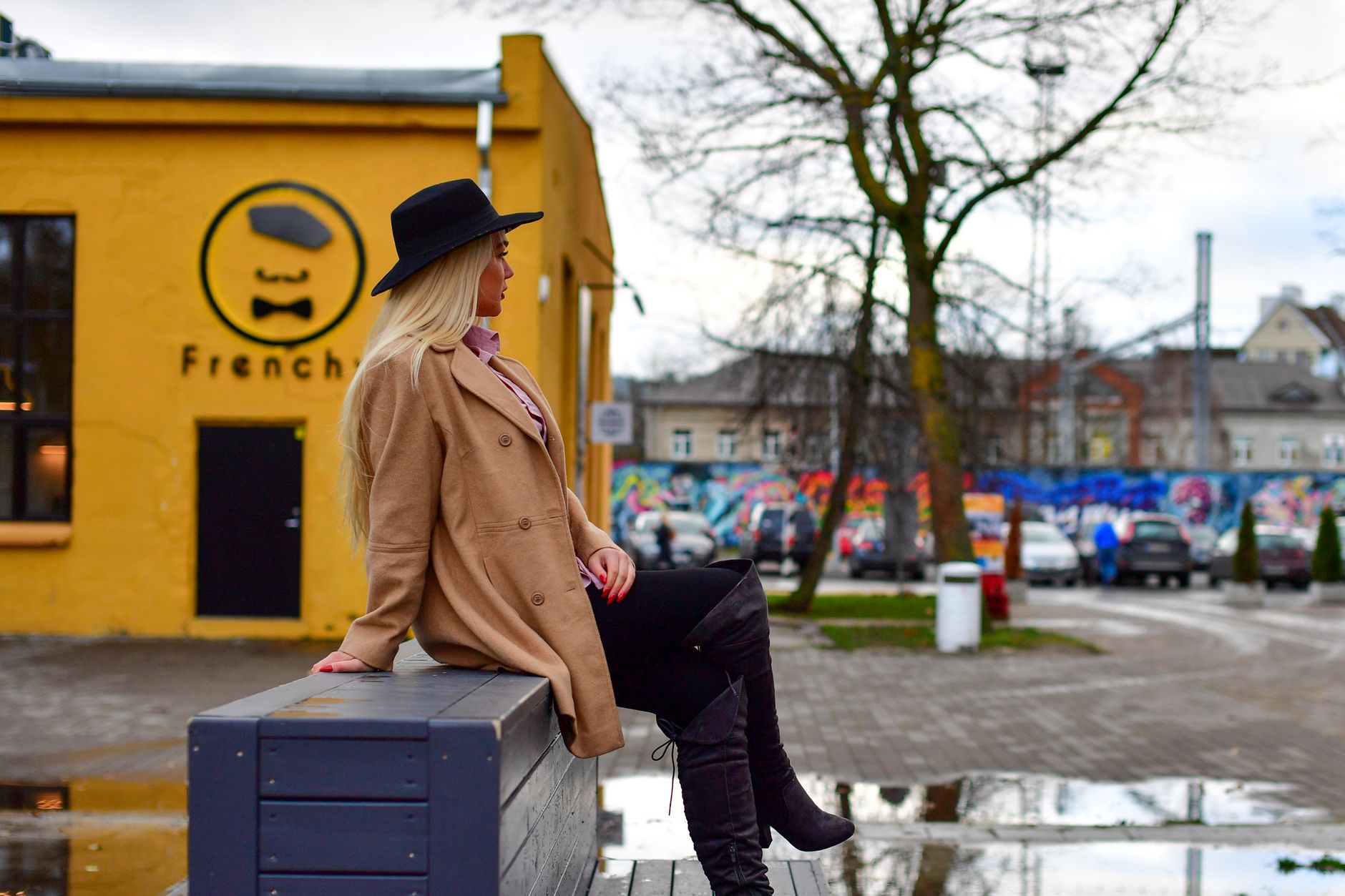 Stylish woman in chic attire enjoys a peaceful moment in Tallinn's Telliskivi Creative City.