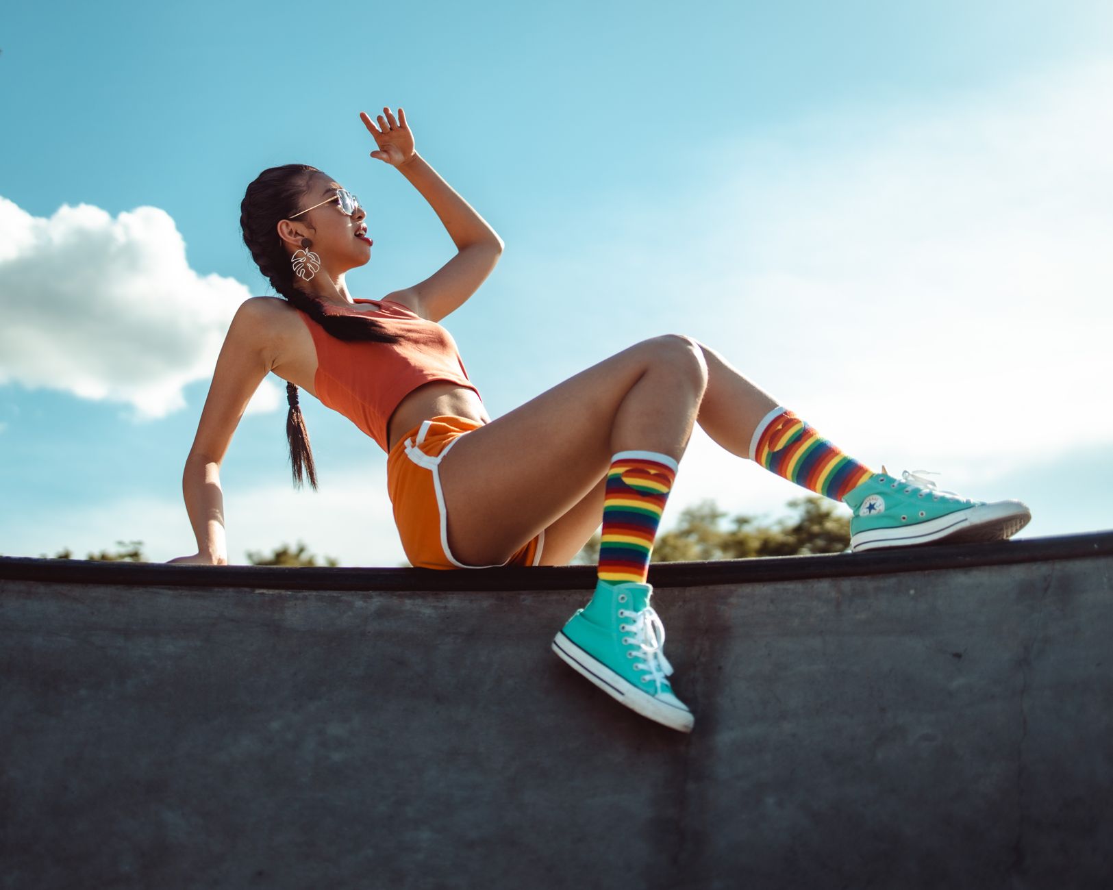 Fashionable woman poses on skate ramp, showing vibrant summer style with colorful socks and sneakers.