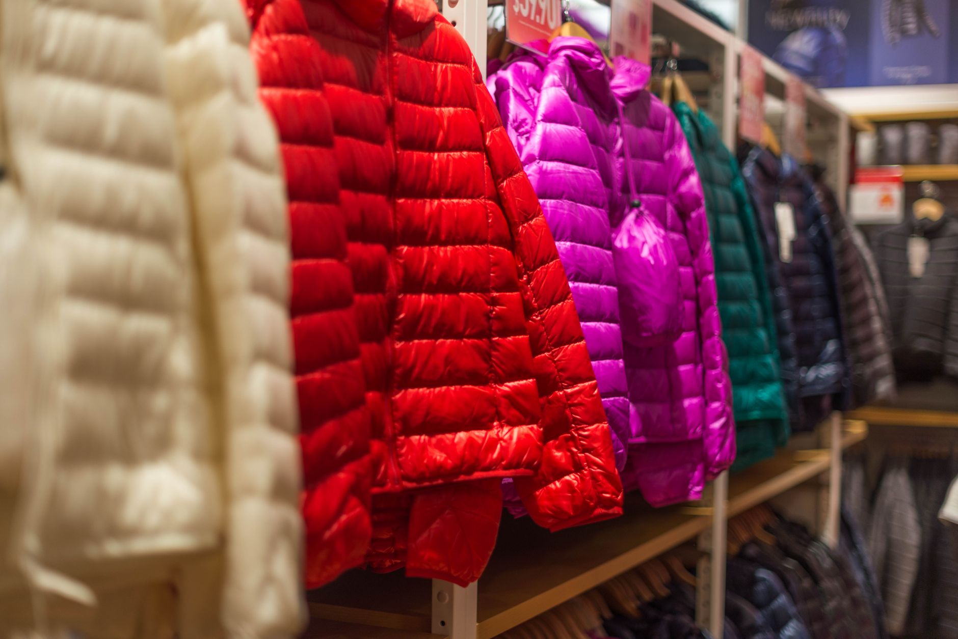 Vibrant winter jackets on display in a clothing store, showcasing a variety of colors for shoppers.