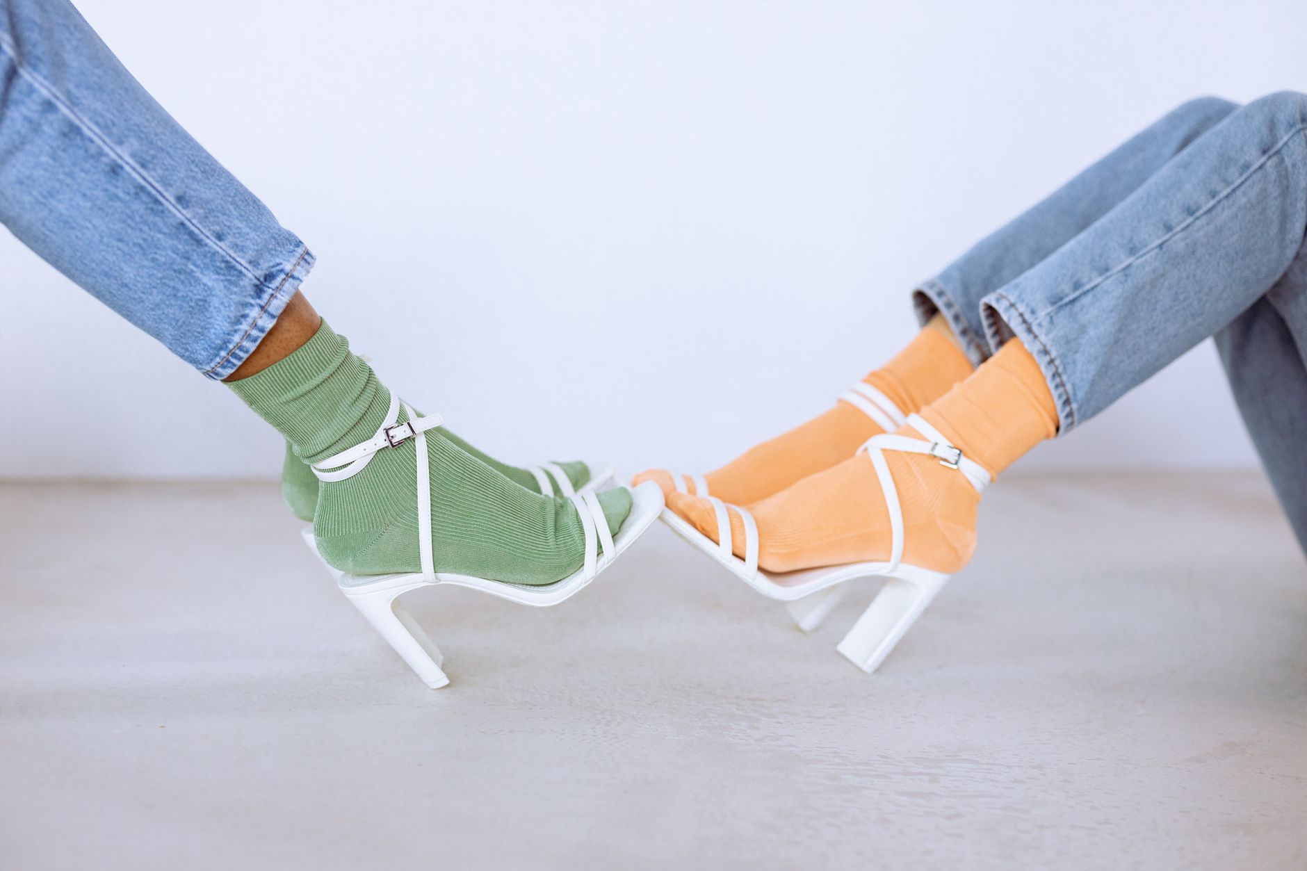 Trendy fashion shot of vibrant socks with white high heels in a studio setting.