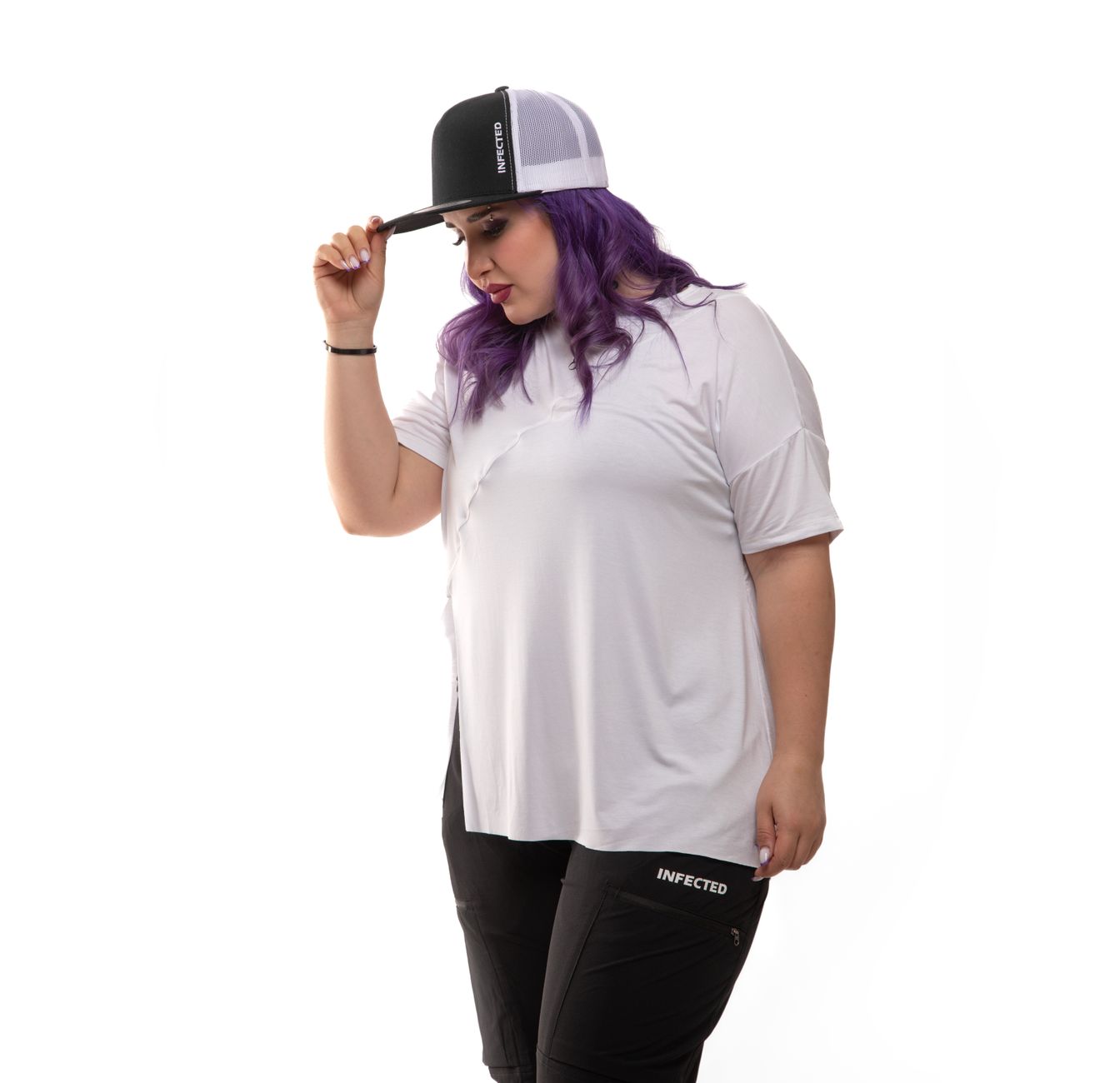 Confident plus size model in white tee and black pants showcases trendy streetwear with colorful hair.