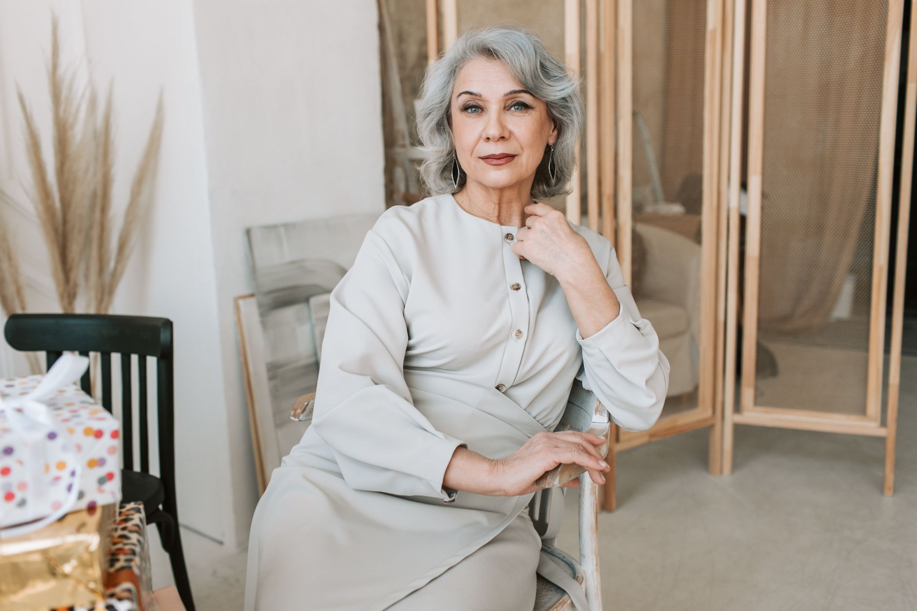 Sophisticated senior woman with silver hair poses gracefully indoors, exuding elegance.