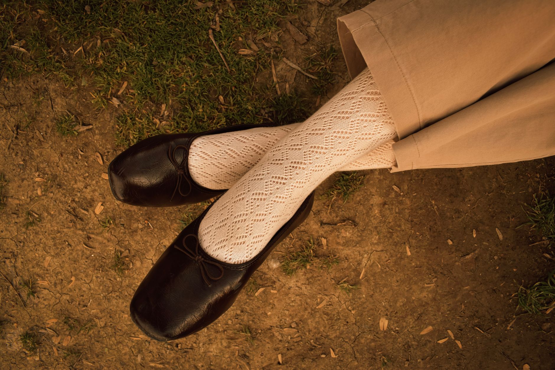 Stylish black ballerina flats with delicate lace tights in a casual outdoor setting.