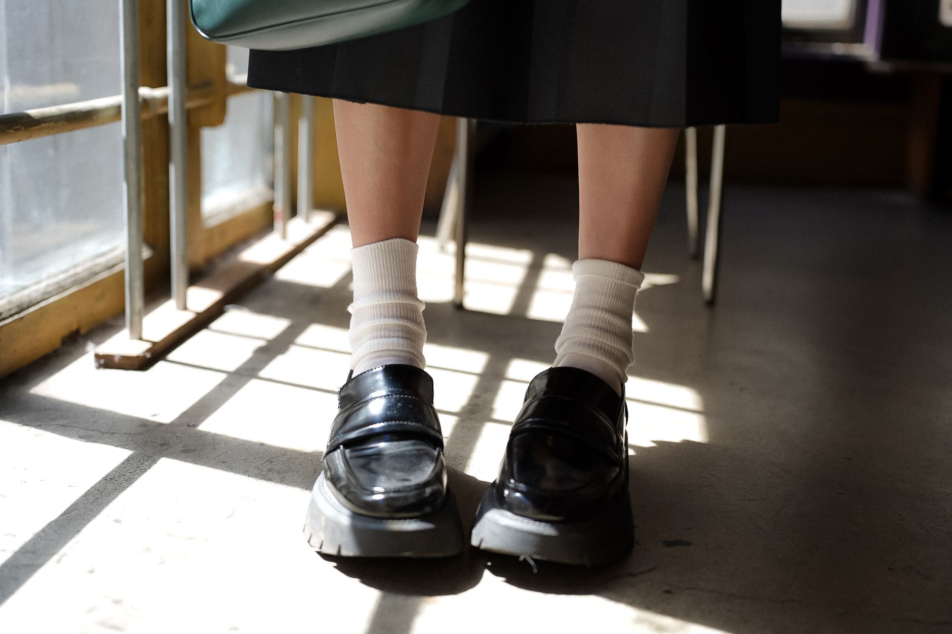 Chic black loafers paired with classic white socks captured in a sunlit indoor setting.