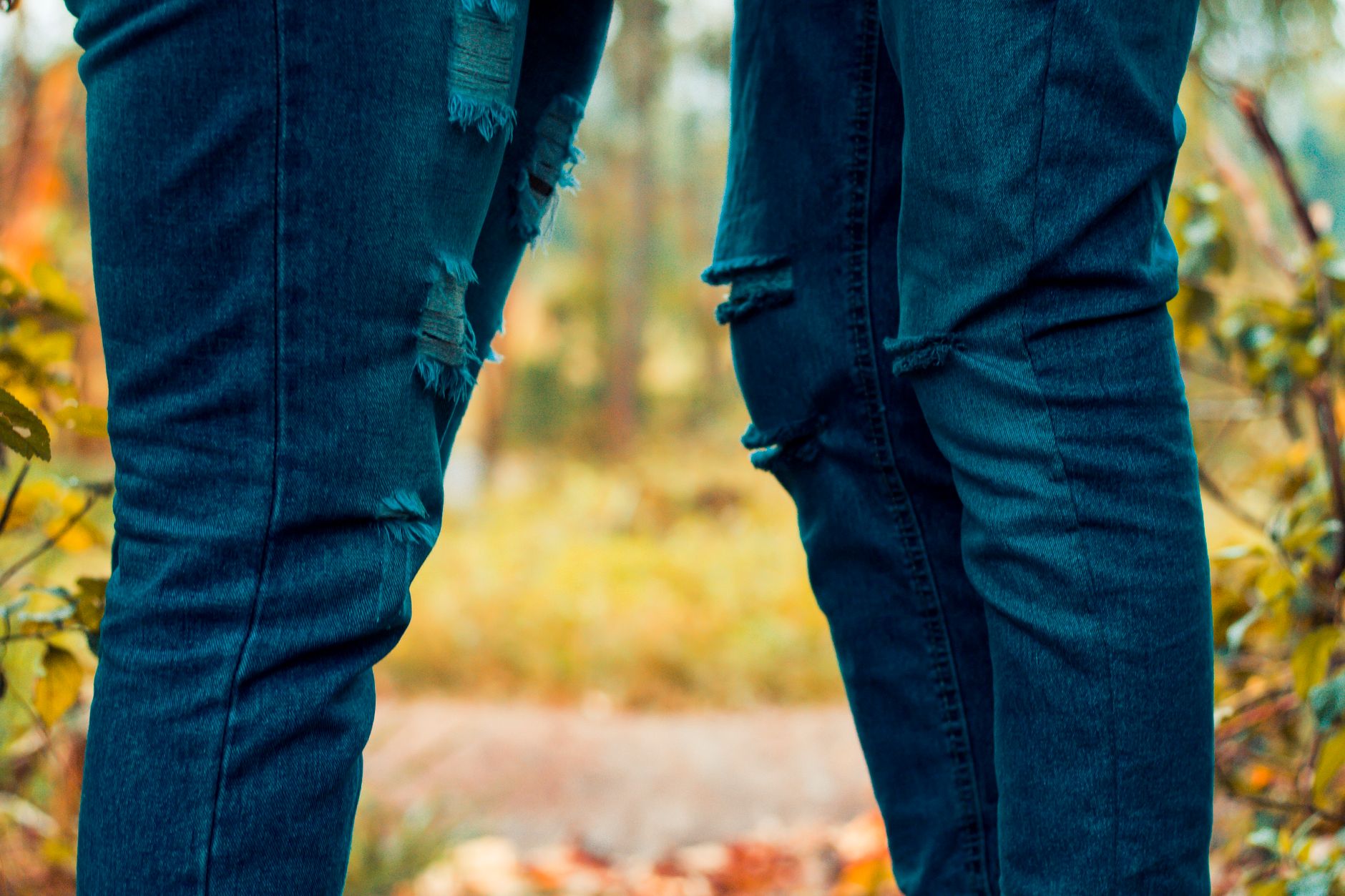 Close-up view of fashionable ripped jeans worn in an outdoor environment.