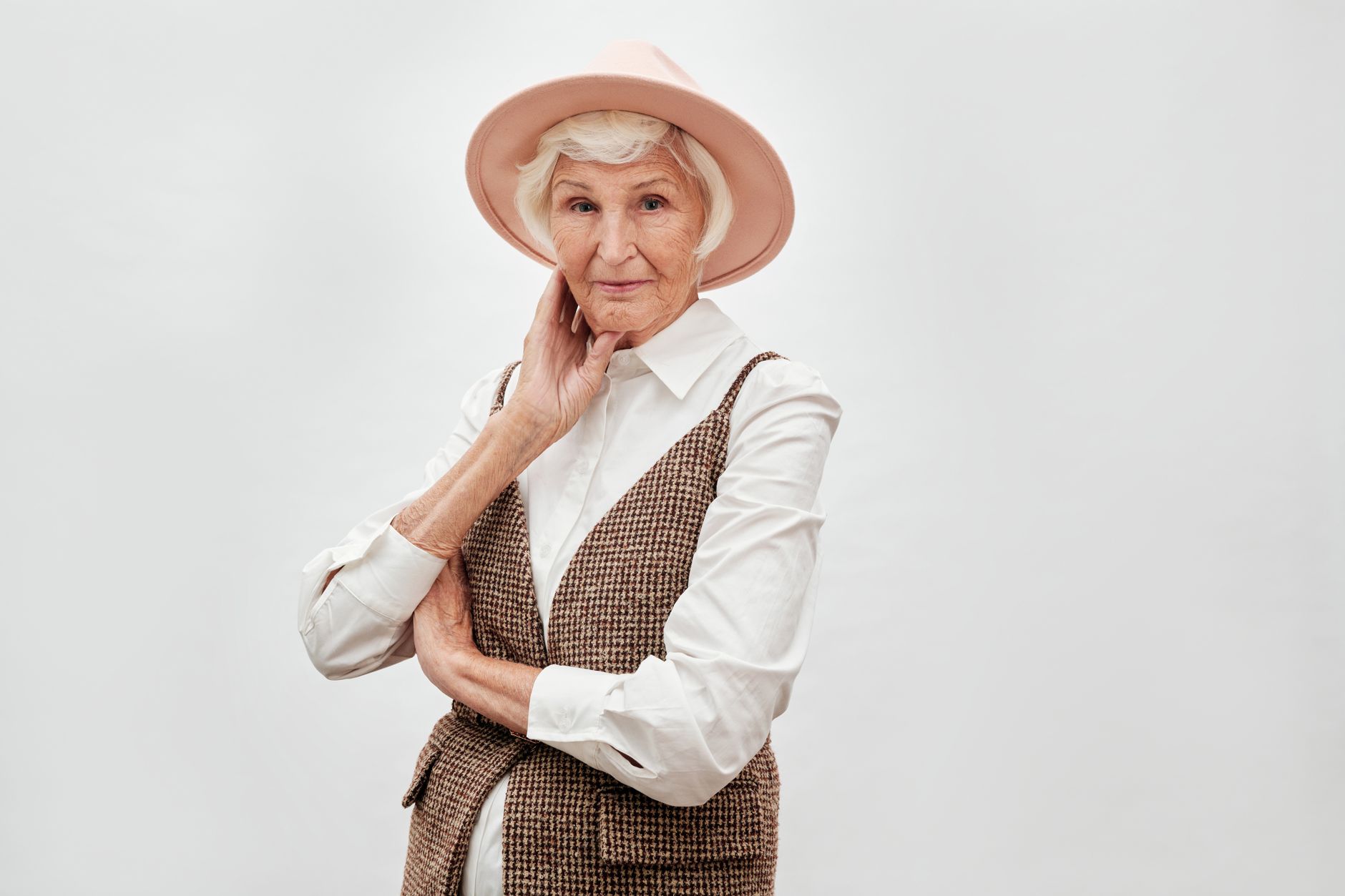 Portrait of a stylish senior woman wearing a fashionable hat and vest, exuding elegance.