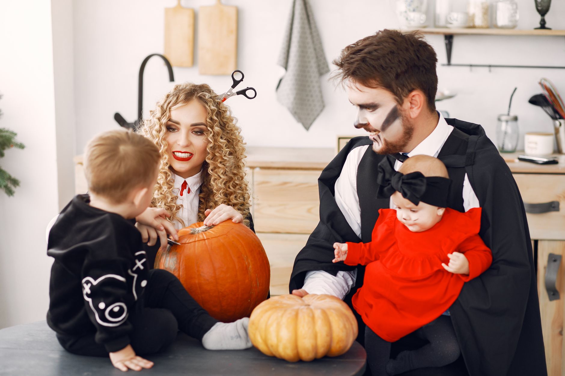 A family in creative Halloween costumes carving pumpkins indoors, showcasing holiday spirit and togetherness.