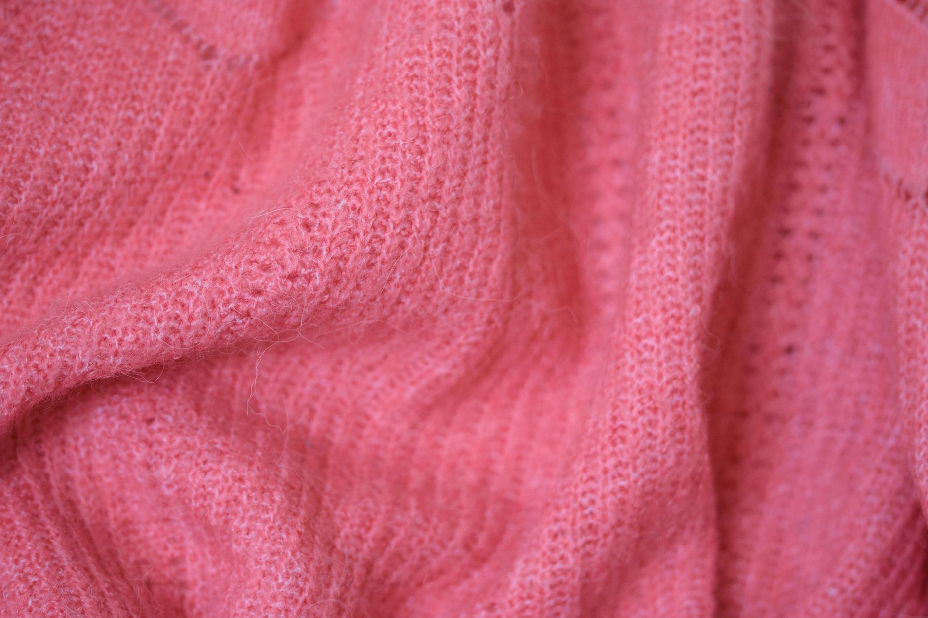 Detailed close-up of warm pink sweater fabric showcases a cozy and soft texture.