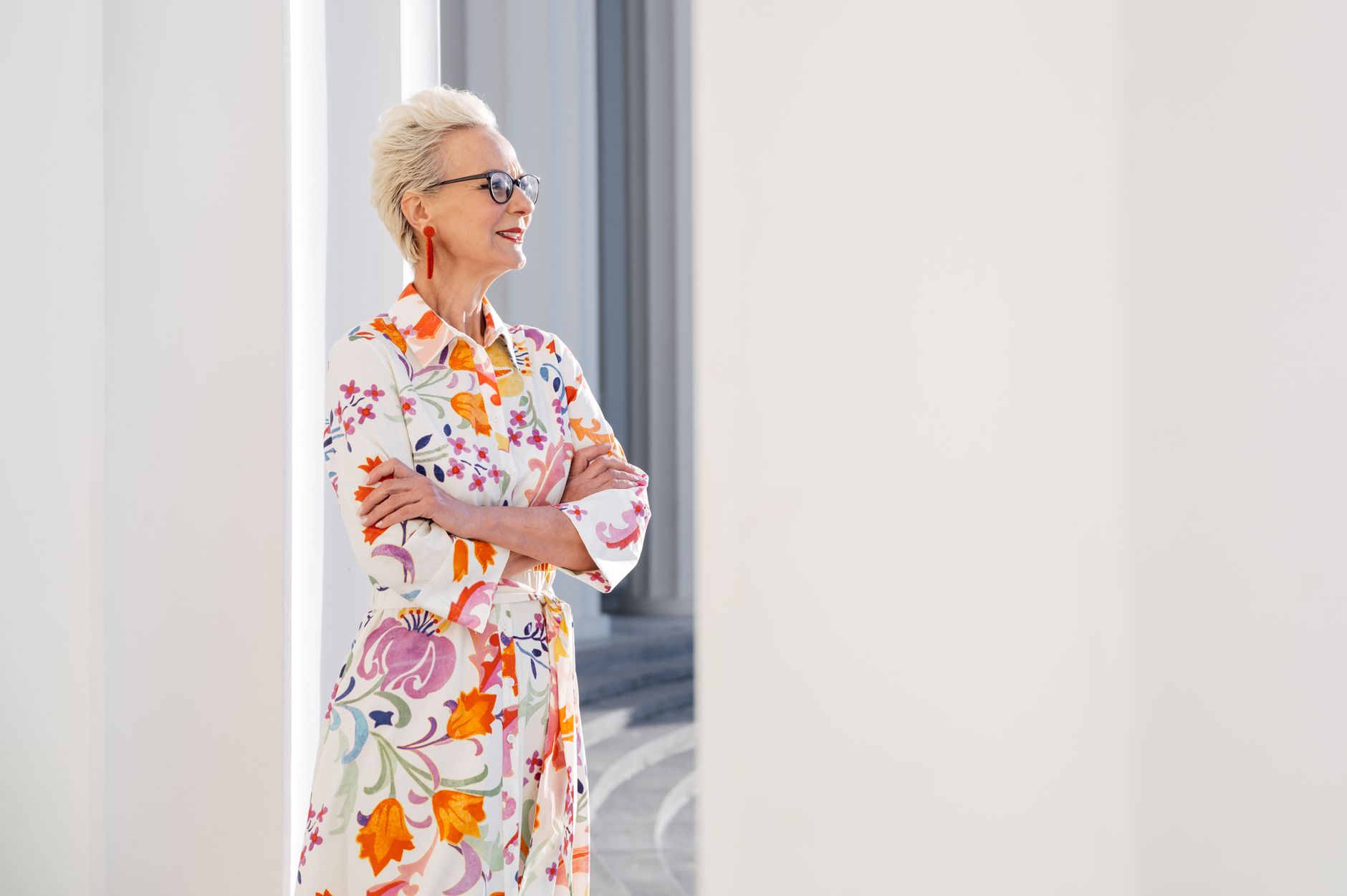 Elegant senior woman wearing a floral dress, smiling confidently outdoors.