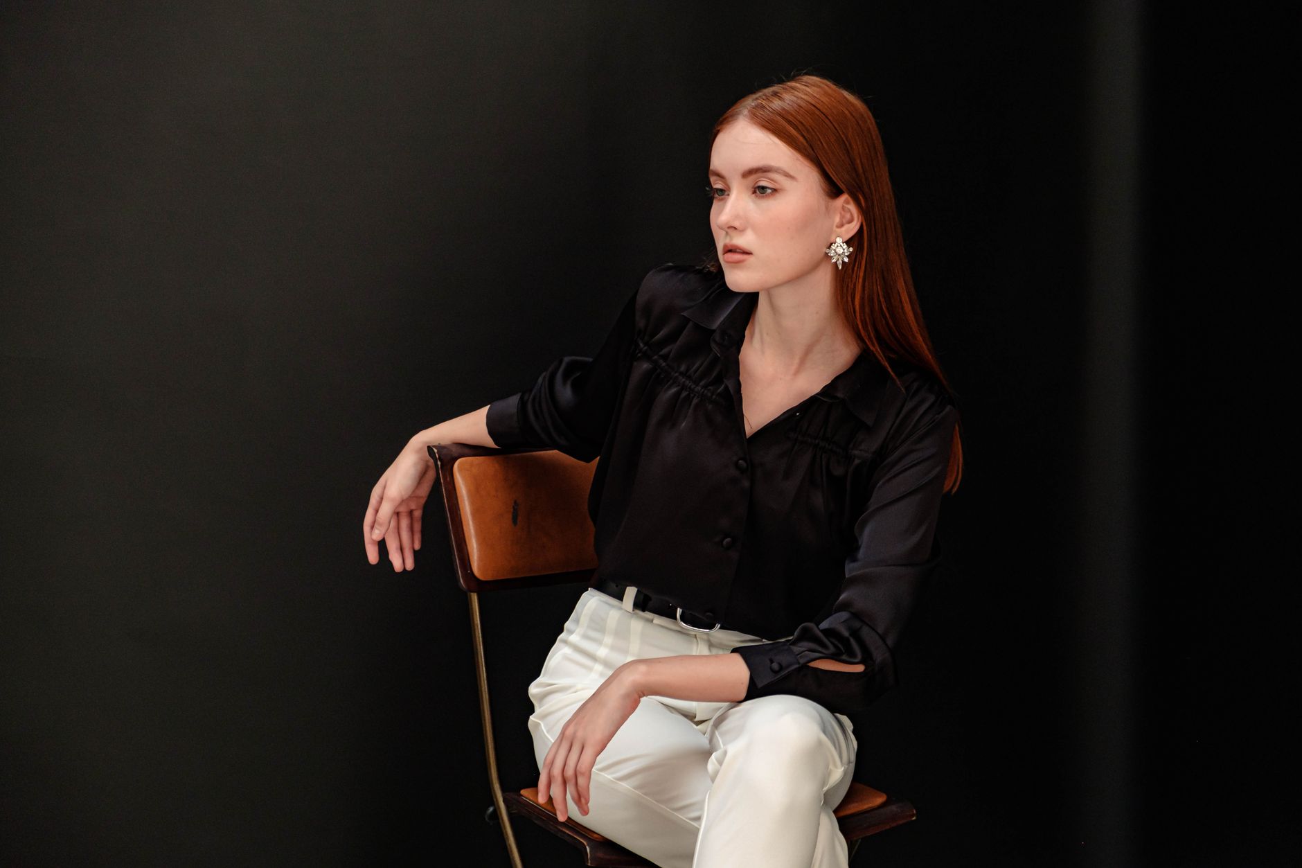 Stylish portrait of a woman in a black blouse posing elegantly in a studio setting.